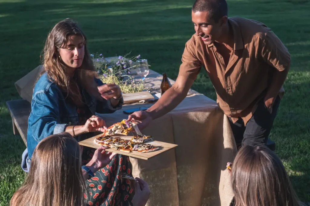Guests sharing freshly served pizza at an outdoor party