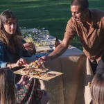 Guests sharing freshly served pizza at an outdoor party